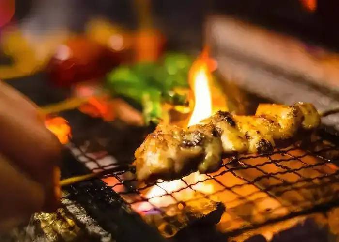 A yakitori skewer being grilled over an open flame.